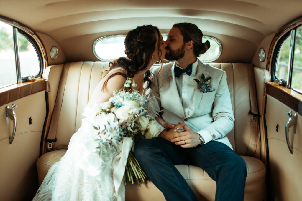 A couple kissing in a stretch limousine on their wedding day